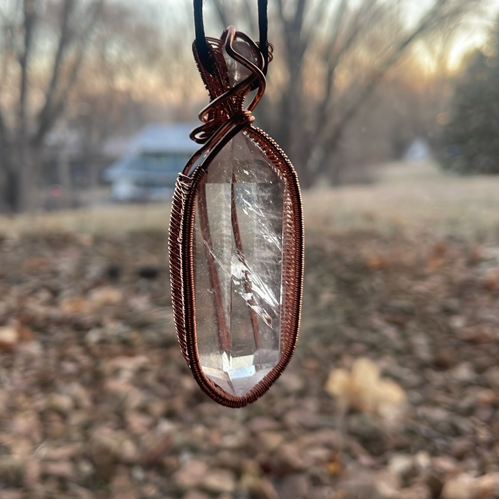Copper wrapped clear quarts necklace with rose quarts stone on top.